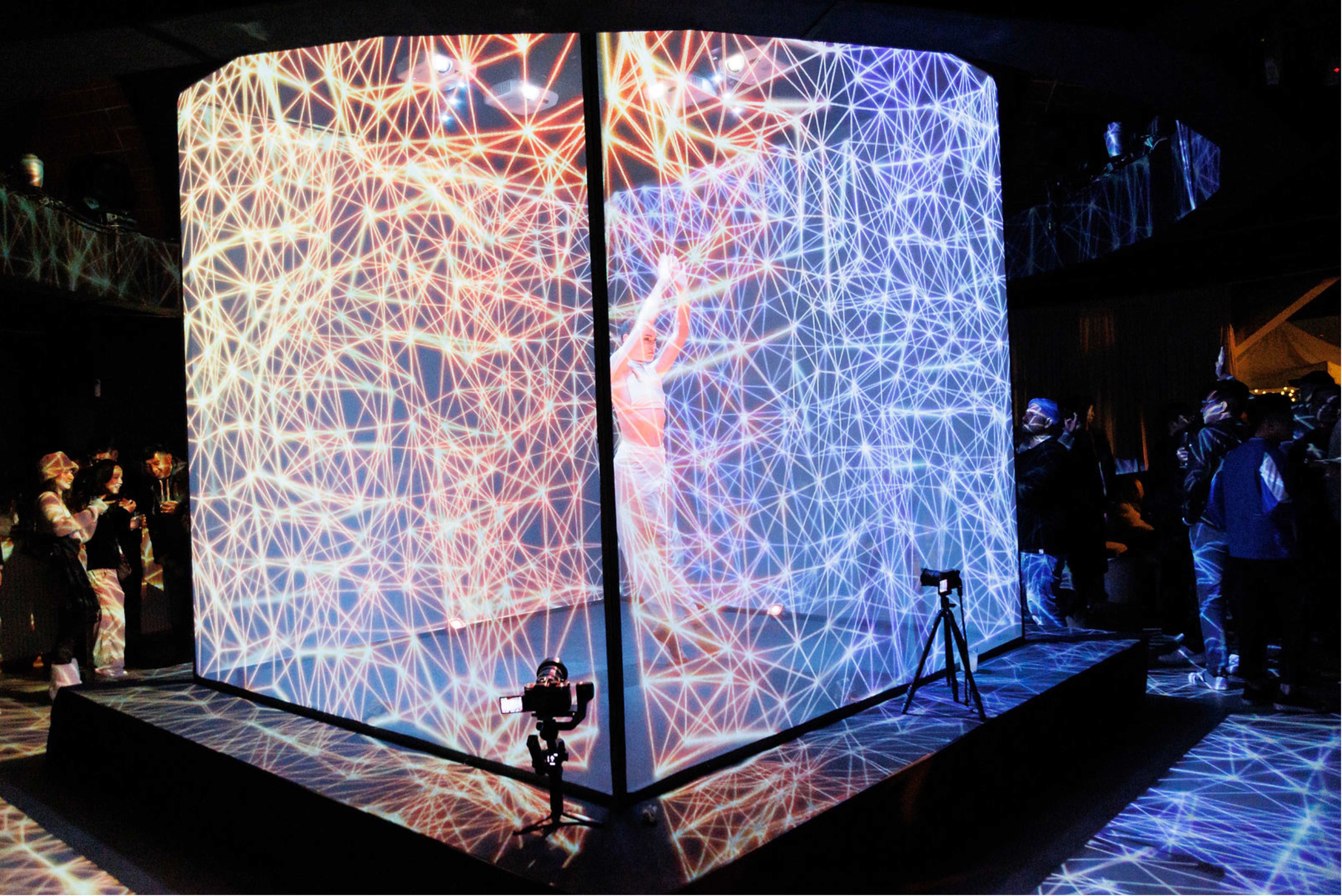  - Live performer interacting with a large, projection-mapped digital cube displaying gaming brand assets at an event