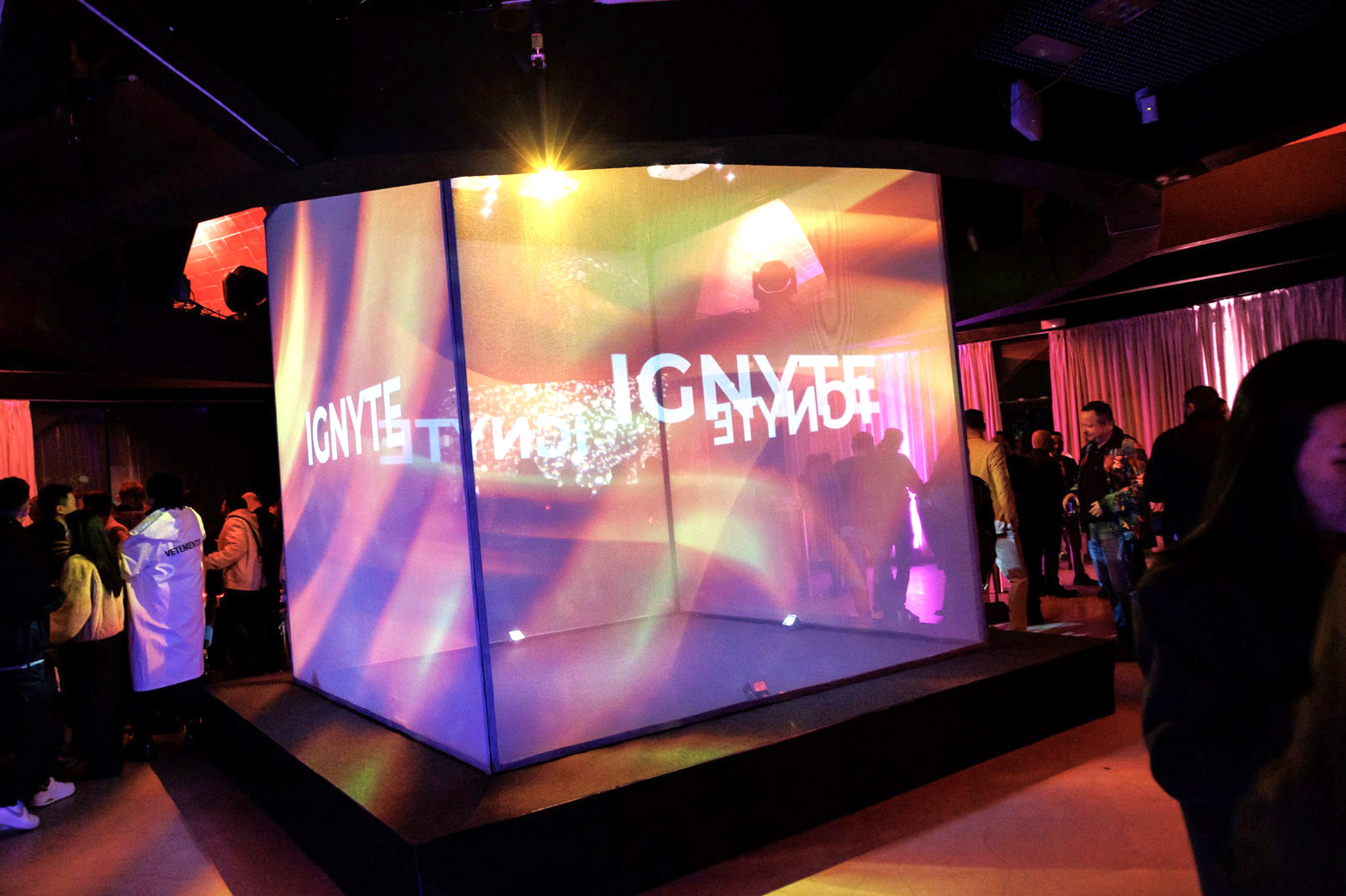 A dramatic orange lighting transition and projection mapping performance on a central cube at a VIP brand partnership event in Barcelona