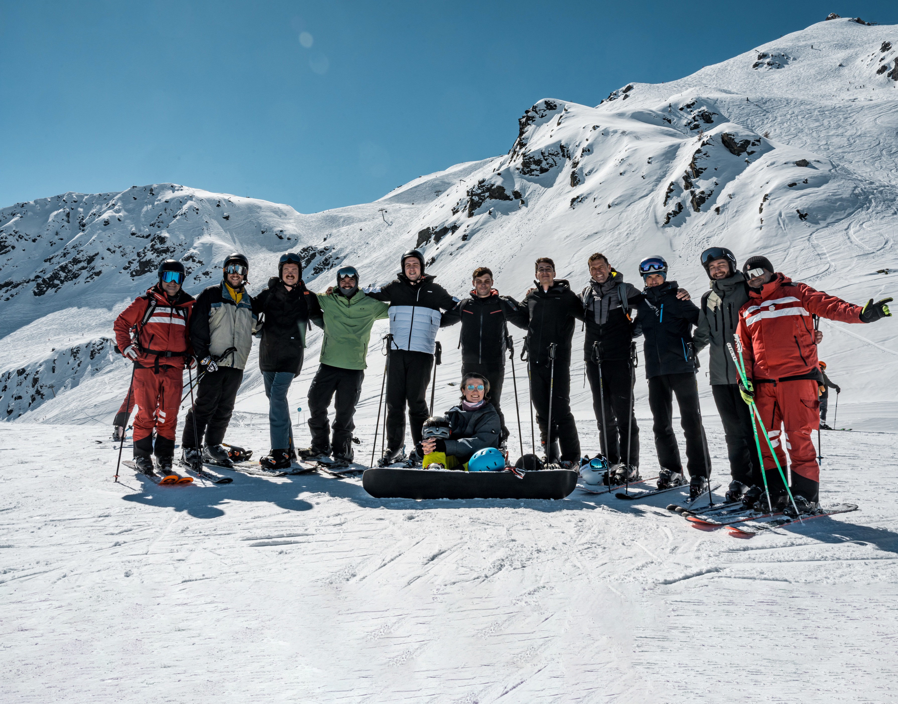 Group of corporate retreat guests standing together in front of snow-covered Alps in Courchevel